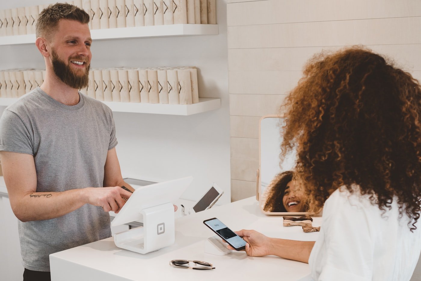 Une cliente présente son téléphone au commerçant en caisse